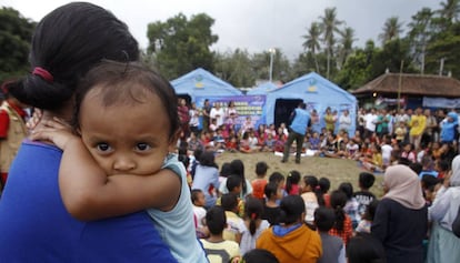 Una mujer carga con su bebé en un refugio temporal para los evacuados de las inmediaciones del volcán Agung en Bali, Indonesia.