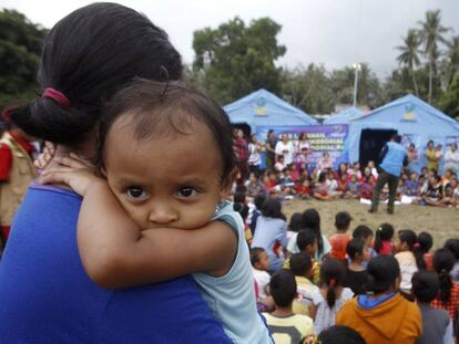 Una mujer carga con su bebé en un refugio temporal para los evacuados de las inmediaciones del volcán Agung en Bali, Indonesia.