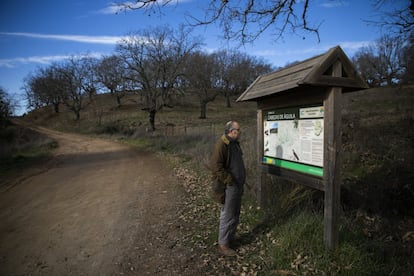 Mario Morales, apicultor, ganadero y miembro de la Plataforma Salvemos las Villuercas, observa un cartel informativo sobre aves protegidas que existen en el entorno, en el municipio de Berzocana (Cáceres).