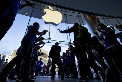 Empleados chinos aplauden a los primeros clientes en commprar los nuevos iPhones en una tienda de Apple en el distrito comercial de Wangfujing en Beijing.