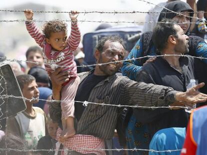 Un refugiado sirio intenta cruzar junto a su niña la frontera con Turquía, el lunes en Akcakale.