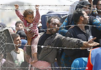 Un refugiado sirio intenta cruzar junto a su niña la frontera con Turquía, el lunes en Akcakale.