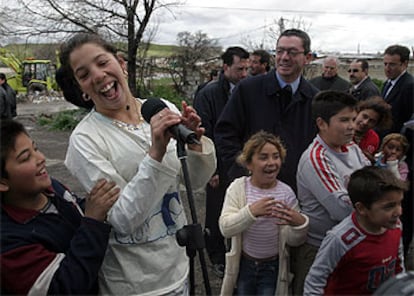 Un grupo de niños y jóvenes de Las Barranquillas <i>se apodera</i> del micrófono que antes había utilizado para su discurso Ruiz-Gallardón (detrás).