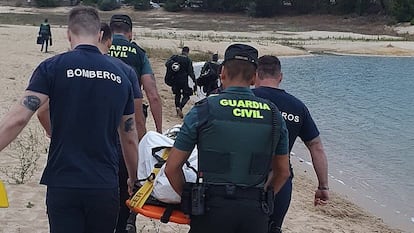 Bomberos y agentes de la Guardia Civil trasladan el cuerpo sin vida del adolescente ahogado en el embalse de Arija en la tarde del jueves.