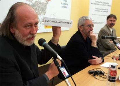 El escritor húngaro László Krasznahorkai muestra un cartel con su nombre junto al autor de origen rumano Adan Bodor y el traductor Adan Kovacsis.