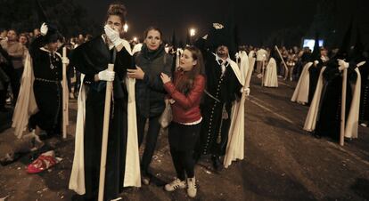 Los incidentes han provocado el pánico entre los asistentes y cortes en las carreras procesionales durante la noche conocida como la Madrugá. En la imagen, nazarenos de La Esperanza de Triana visiblemente afectados tras sufrir una estampida durante su recorrido procesional a su paso por el puente de Triana.