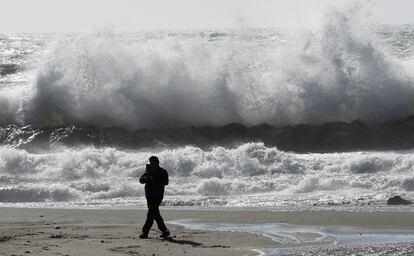 Una persona pasea por la playa de El Zapillo, en Almería, durante el temporal de viento que azota la provincia y por la que la AEMET ha declarado la alerta naranja por rachas de hasta 80 km/h, este martes.
