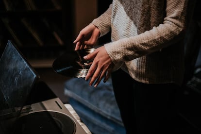 Una mujer pone un vinilo. 