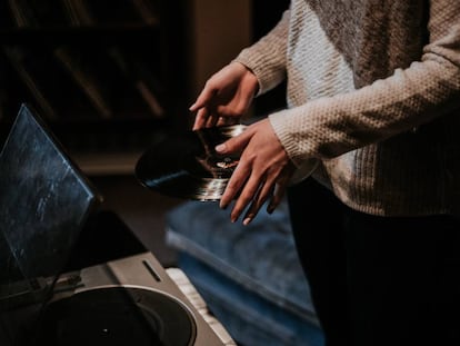 Una mujer pone un vinilo. 