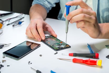 Un técnico electrónico repara un teléfono móvil.