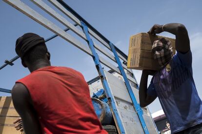 Los vecinos de una aldea cercana ayudan a cargar un camión con cajas de alimentos terapéuticos listos para usar para entregar al pueblo de Guihoyo después de que un coche de AMCP-ALIMA quedara atascado en el barro.