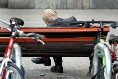 Un anciano dormita en uno de los bancos de la plaza de Catalunya de Barcelona
