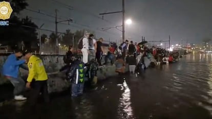 Elementos de la Secretaría de Seguridad Ciudadana ayudan transeúntes atrapados entre las vías inundadas tras las intensas lluvias de este lunes.