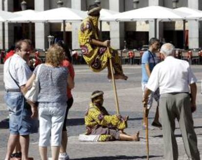 Unos hombres posan como estatuas vivientes para los turistas en la madrileña Plaza Mayor. EFE/Archivo