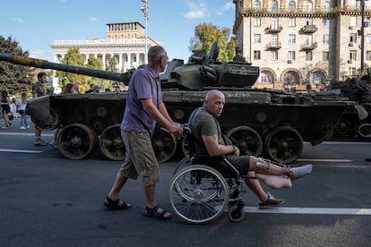 A man pushes a Ukrainian serviceman's wheelchair during Independence Day celebrations