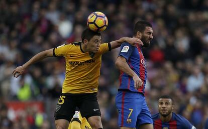 Federico Ricca (esquerra) del Màlaga copeja la pilota davant la pressió d'Arda Turan.