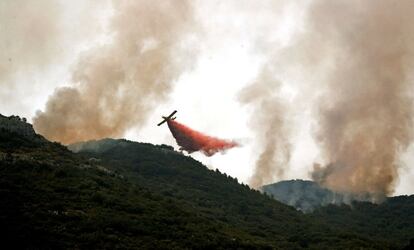 Una avioneta lanza agua con retardantes sobre el frente del incendio que se acerca a la localidad de Barx, el 7 de agosto.