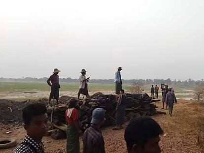 Men stand over a funeral pyre in Tar Taing village, as they prepare to cremate bodies of those found dead in the nearby village of Nyaung Yin, on Thursday, March 2, 2023.