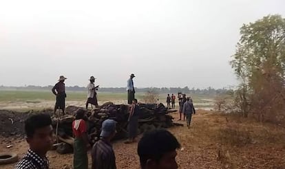 Men stand over a funeral pyre in Tar Taing village, as they prepare to cremate bodies of those found dead in the nearby village of Nyaung Yin, on Thursday, March 2, 2023.