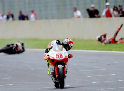 Marco Simoncelli mira a Héctor Barberá, caído en el suelo tras su choque con el piloto italiano.