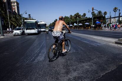 Un hombre en bañador circula en bicicleta por el centro de Málaga,
