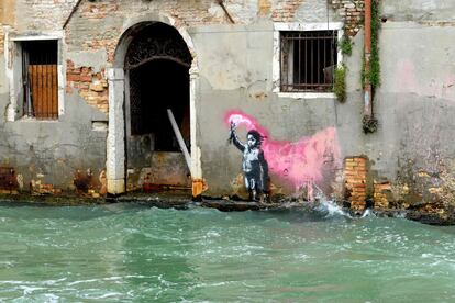 Una supuesta obra de Banksy que representa a un niño migrante vestido con un chaleco salvavidas y una bengala rosa, pintada sobre la fachada de una casa en el canal del Rio de Ca Foscari, en Venecia.