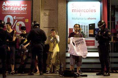 La policia identifica al fotoperidista Gabriel Pecot durante el desalojo de las 200 personas que permanecían en la Puerta del Sol después de la primera de las concentraciones autorizadas por la Delegación del Gobierno en Madrid, sobre las 5:00 horas.