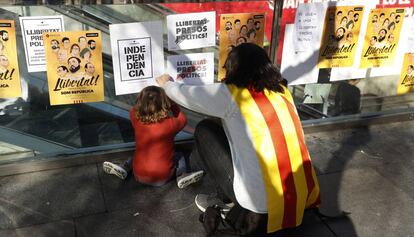 Una mujer y un niño pegan carteles por la independencia catalana el 5 de noviembre.