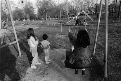 Varios ni?os juegan en unos columpios de un parque en la Casa de Campo de Madrid.