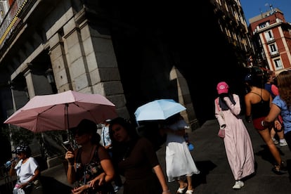 Turistas se cubren con paraguas en la Plaza Mayor de Madrid, en agosto.
