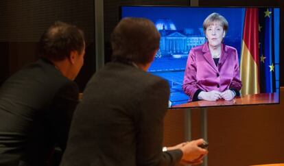 Funcionarios alemanes miran el v&iacute;deo del mensaje de Merkel.