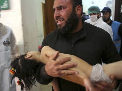 Un hombre lleva en brazos a un niña a urgencias en la localidad atacada con armas químicas.