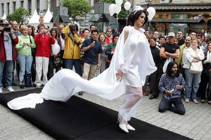 Una mujer exhibe un vestido de boda durante el desfile callejero ante decenas de personas.