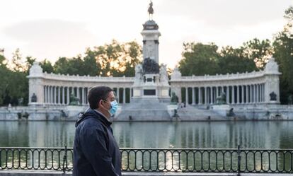 Un hombre con mascarilla camina junto al Estanque en el Parque del Retiro de Madrid