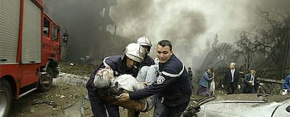 Dos bomberos trasladan a un herido en los atentados de Argel