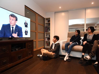 Uma família assiste na televisão o pronunciamento de Emmanuel Macron sobre as novas medidas de restrição para conter a covid-19 na França.