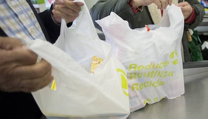 Unos clientes de un supermercado de Sevilla llenan bolsas de plástico con la compra.