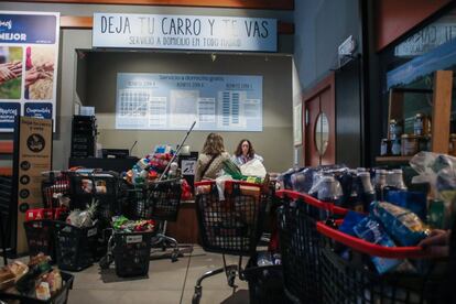 Dos clientas de un supermercado del centro de Madrid entregan sus compras para su posterior entrega a domicilio.