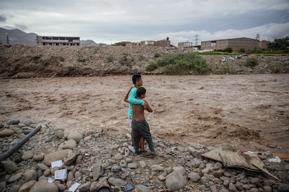 Dos niños miran conmovidos el caudal furioso de un río costero. Sus familias tienen que vivir donde pueden. Por lo general en modestas viviendas de madera.