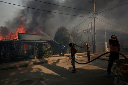 Bomberos y voluntarios tratan de contener las llamas de un incendio, este sábado en la periferia de Atenas.