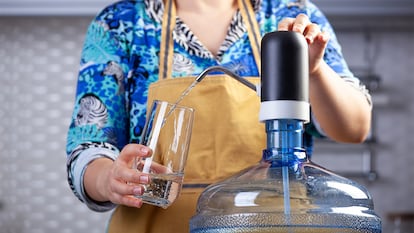 Una mujer echando agua en un baso con el dispensador automático.