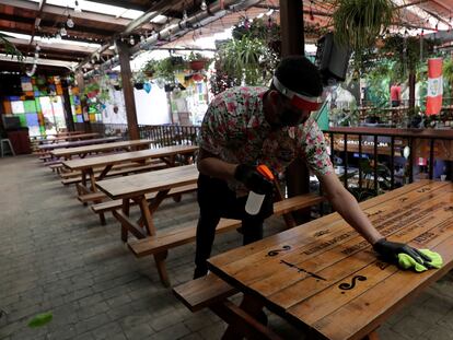 Un mesero limpia una mesa mientras espera la reapertura del restaurante Comedor de los Milagros en Ciudad de México.