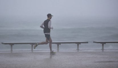 Un ‘runner’ corre bajo una intensa lluvia junto al mar, en el litoral de Barcelona.