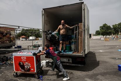 Dos operarios recogen su puesto ambulante en el mercadillo de Parla.