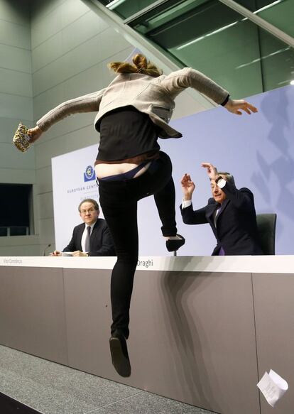 Una activista salta damunt la taula en la qual Mario Draghi, president del Banc Central Europeu, començava la roda de premsa després de la reunió del consell de l'organisme.