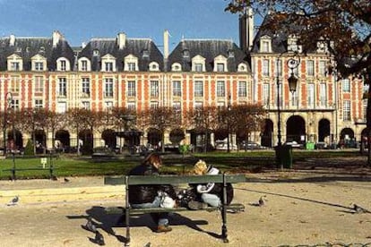 Una pareja de parisienses sentada en un banco de la Place des Vosges.