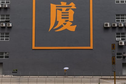 Una mujer camina junto a una vieja fábrica que ha sido reconvertida en edificio de oficinas en Kwai Hing, Hong Kong.