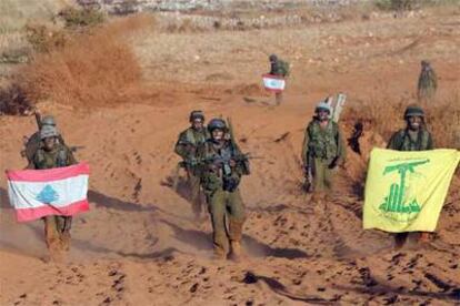 Soldados israelíes sostienen una bandera libanesa (izquierda) y otra de Hezbolá al retirarse del sur de Líbano.