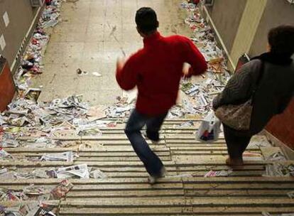 Dos viajeros acceden a una estación del metro de Madrid repleta de basura.