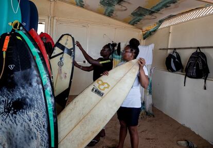 Khadjou Sambe elige una tabla de surf mientras habla con su entrenadora, Rhonda Harper, fundadora de Black Girls Surf (BGS), una escuela de formación para niñas y mujeres que quieren competir en el surf profesional. En Ngor, Dakar, Senegal, el 12 de agosto de 2020. Sambe fue a California en 2018 para entrenar con BGS. Harper cuenta que llegó sin un centavo en el bolsillo, sin hablar inglés y con un estilo de surf libre y salvaje que necesitaba ser domesticado para adaptarse a la estructura de las competiciones de surf. "Es como tratar de tomar un tornado a la derecha, y poner una cuerda alrededor, hacer que esa cosa se baje. Porque ella es una surfista tan dinámica que es difícil". Harper explica que BGS comenzó a buscar surfistas femeninas en África debido a la falta de representación en el surf profesional.